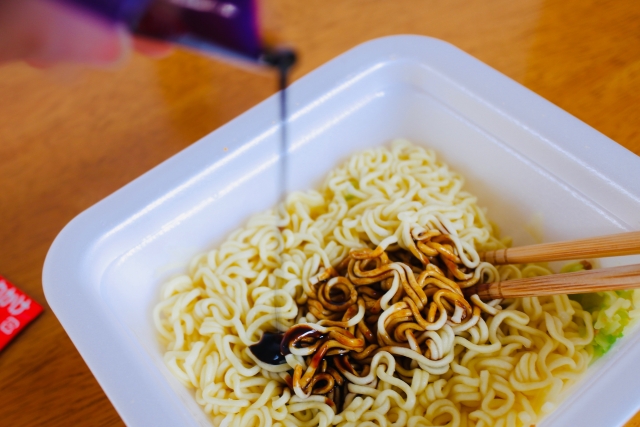 お湯でふやかした焼きそば麺に茶色いソースをかけている画像